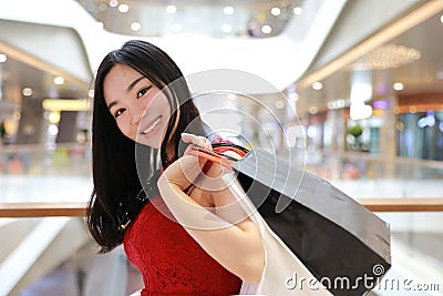 Happy Asian Chinese modern fashionable woman shopping bags in a mall store casual buyer smile laugh consumption on sale promotion Stock Photo