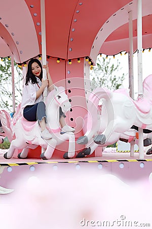 Happy Asian Chinese woman girl on Merry-go-round in a Amusement Park Stock Photo