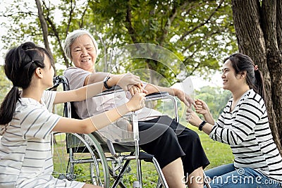 Happy asian daughter,granddaughter holding hand her senior mother care,support and massaging hands of elderly people at park,old Stock Photo