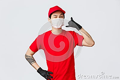 Happy asian delivery guy in medical mask tell give call, wink cheeky to client, keep in touch when delivery needed, fast Stock Photo