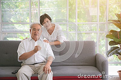 Happy asian elderly couple in love drinking milk togetherness at the living room. Healthy food concept Stock Photo