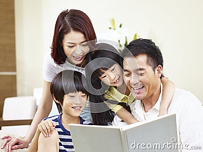 Happy asian family reading a book at home Stock Photo