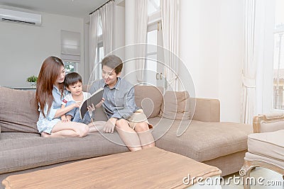 Happy asian family reading storybook at home Stock Photo