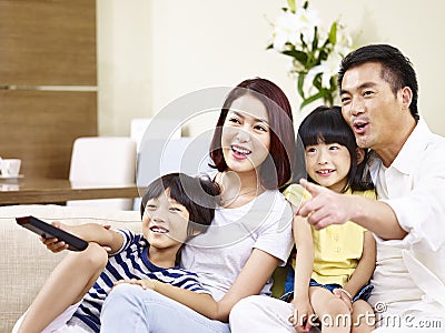 Happy asian family watching TV at home Stock Photo