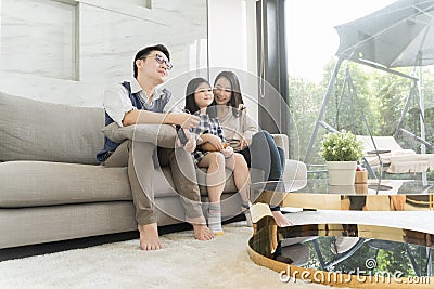 Happy asian family watching tv together on sofa in living room. family and home concept. Stock Photo