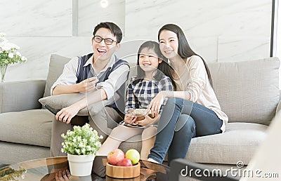 Happy asian family watching tv together on sofa in living room. family and home concept. Stock Photo