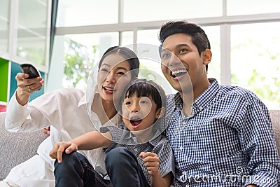 Happy asian family watching tv together on sofa in living room. family and home concept. Stock Photo