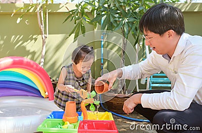 Happy Asian father and daughter having fun playing with water table at home, Wet Pouring Montessori Preschool Practical Life Stock Photo