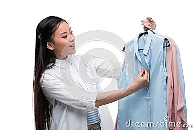 Happy asian girl choosing blouses, isolated on white Stock Photo