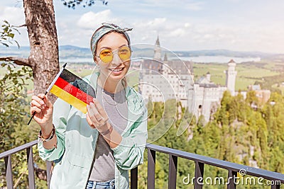 Asian traveller girl eats crispy pretzel in the background of the legendary Neuschwanstein castle. Tourism in Bavaria Stock Photo