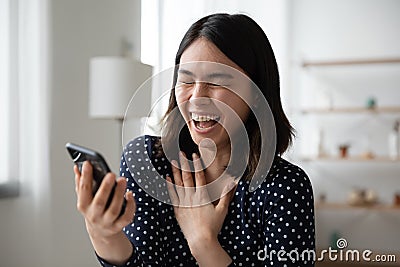 Happy Asian girl laugh watching video on cellphone Stock Photo