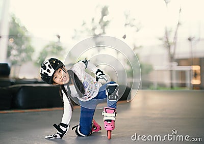 Happy Asian girl learning to roller skate. Children wearing protection pads for safe ride. Active outdoor sport for kids Stock Photo