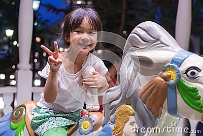 Happy Asian girl riding on a horse merry go round. Stock Photo