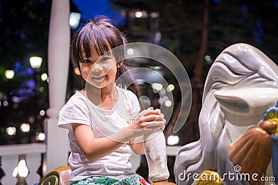 Happy Asian girl riding on a horse merry go round. Stock Photo