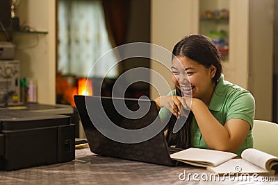 Happy Asian high school girl laughing at laptop Stock Photo