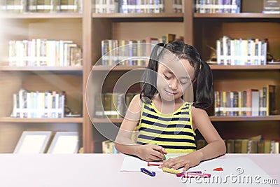 Happy asian little girl drawing on paper with crayon Stock Photo