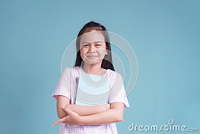 Happy Asian little girl standing holding the book on blue background isolated Stock Photo