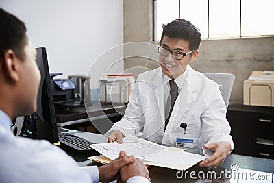 Happy Asian male doctor in consultation with male patient Stock Photo