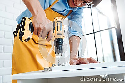 Happy asian man home improvement Assembling Furniture Reads Instructions and Tightens Screw with a Drill. Moving into New House Stock Photo