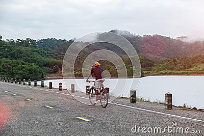 Happy Asian Man Riding Bicycle on Rural Road Look To Nature Ready to Start Vacation Go Adventure Trip, Explore, Discover World Editorial Stock Photo