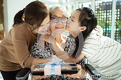 Happy asian mother,daughter meeting old grandparent,giving grandmother a gift,hugging,female elderly hold present box,woman,child Stock Photo