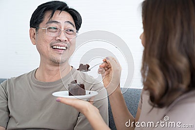 Happy Asian Senior Couple, Wife bakes a cake for her husband to eat. Stock Photo