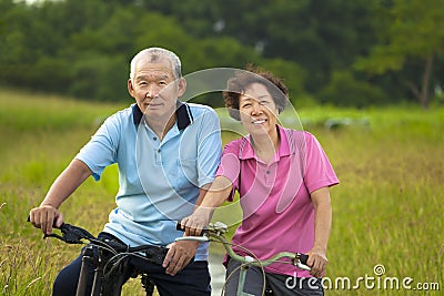 Happy Asian seniors couple biking in Park. Stock Photo