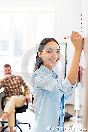 happy asian student girl writing on whiteboard during lesson with blurred teacher Stock Photo