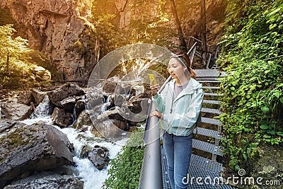 Asian tourist girl walk along a hinged iron trail along sheer cliffs in the canyon of the Pollat river in the Bavarian Alps Stock Photo