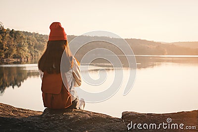 Happy Asian woman sitting on rock in nature during sunset Stock Photo