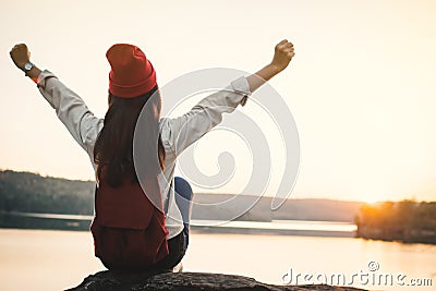 Happy Asian woman sitting on rock in nature during sunset Stock Photo