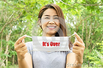 Happy Asian woman smiling and take off protective mask with word its over for covid-19 quarantine ended, we win, we are safe Stock Photo