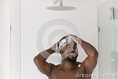 Happy athletic handsome African guy washing hair, taking shower Stock Photo