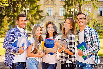 Happy attractive diverse five students standing near university and holding notebook Stock Photo