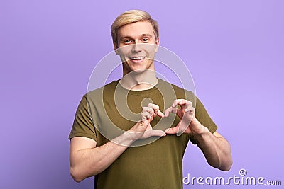 Happy attractive young man, holding hands in heart gesture , Stock Photo