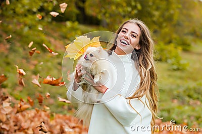 Happy Autumn. Woman having fun with little dog in fall park outdoors. Emotional support. Stock Photo