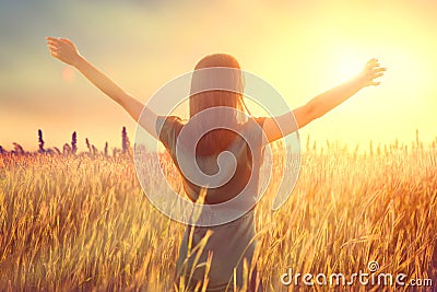 Happy autumn woman raising hands over sunset sky, enjoying life and nature. Beauty female on field looking on sun Stock Photo
