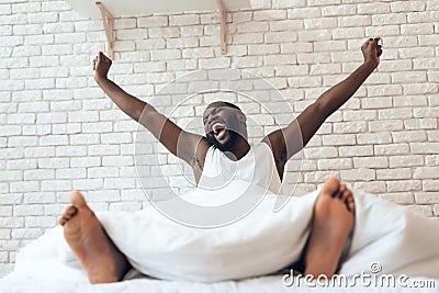 Happy awakened man is stretched out in bed. Stock Photo