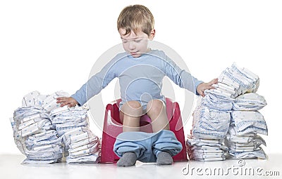 Happy baby boy sitting on chamber pot tearing down diaper piles Stock Photo