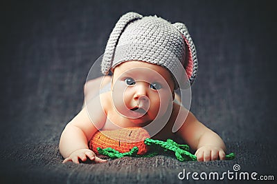 Happy baby child in costume a rabbit bunny with carrot on a grey Stock Photo