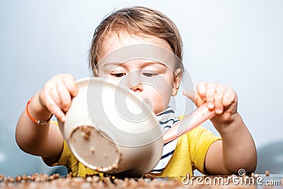 Happy baby child with a spoon. Baby eating. Kid plays in the kitchen with dishes. Happy baby boy spoon eats itself. Stock Photo