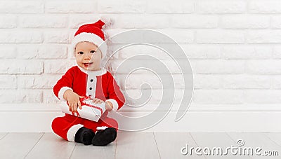 Happy baby in a Christmas costume Santa Claus with gifts Stock Photo