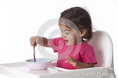 Happy Baby girl is eating by herself Stock Photo