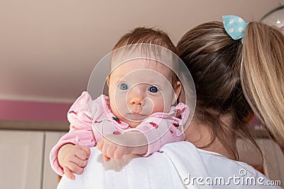 Happy baby girl on mother shoulder. Loving mother hold baby to burp after breastfeeding. The baby girl is 2 months old Stock Photo