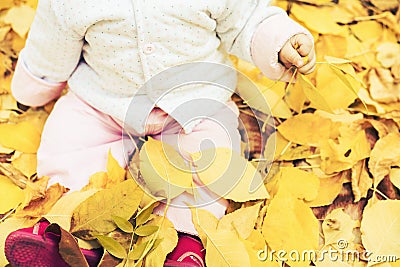 Happy baby outdoor at autumn park sitting on yellow leaves Stock Photo