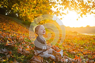 Happy baby playing with leaves in nature. Golden autumn. Smiling little boy with blonde hair plays at beautiful sunny Stock Photo