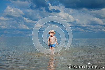 Happy baby running from surf on the beach Stock Photo