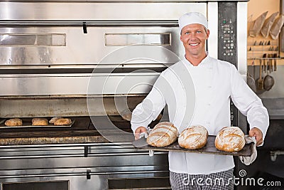 Happy baker holding tray of fresh bread Stock Photo