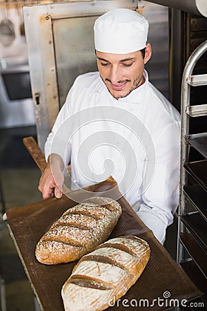 Happy baker holding tray of fresh bread Stock Photo