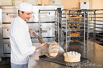 Happy baker taking out fresh loaf Stock Photo